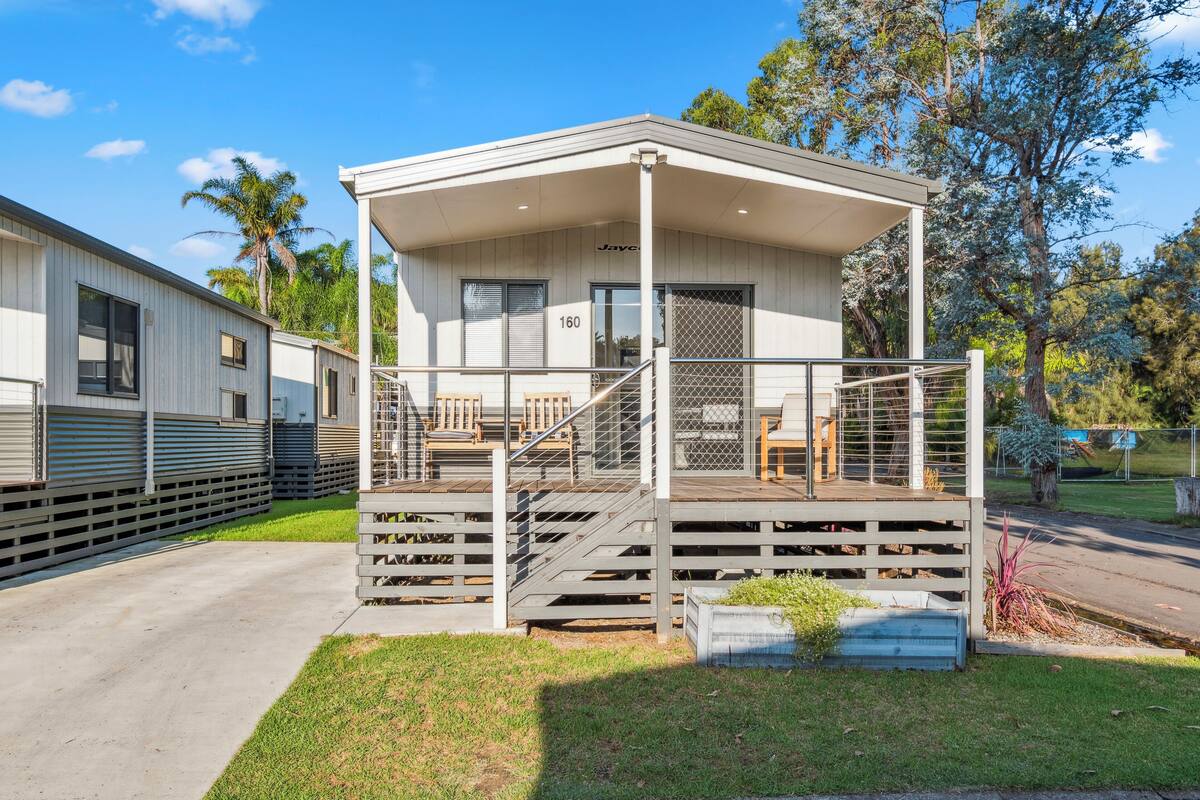A single-story building with a covered porch, a staircase, and a small outdoor seating area.