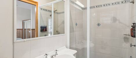 A bathroom with a white sink, mirror, and shower area.