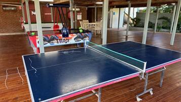 Enjoy a game of ping pong in our recreational area, featuring a table with a metal frame and wheels.