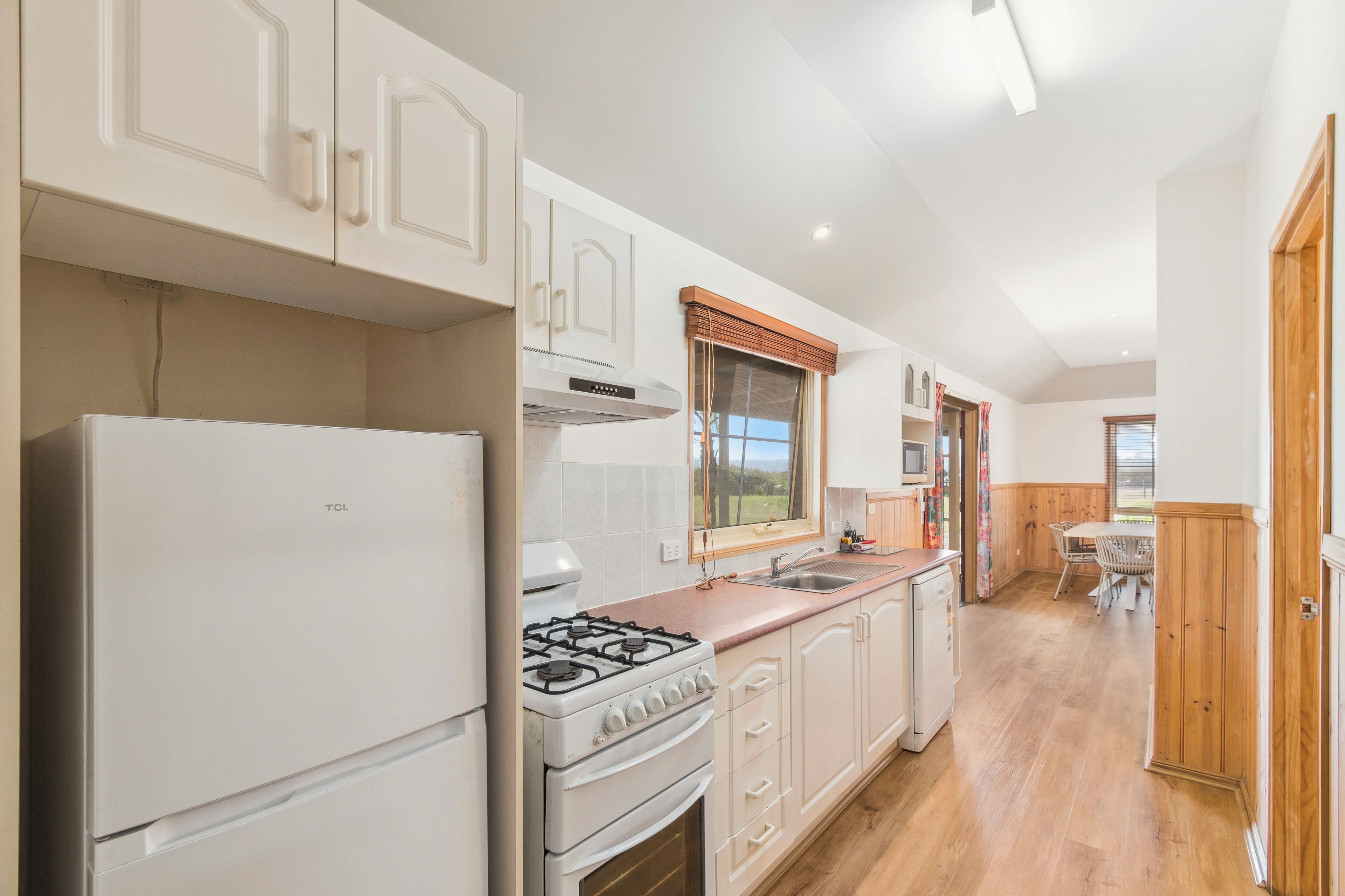 A kitchen with white cabinets, a gas stove, and a refrigerator.