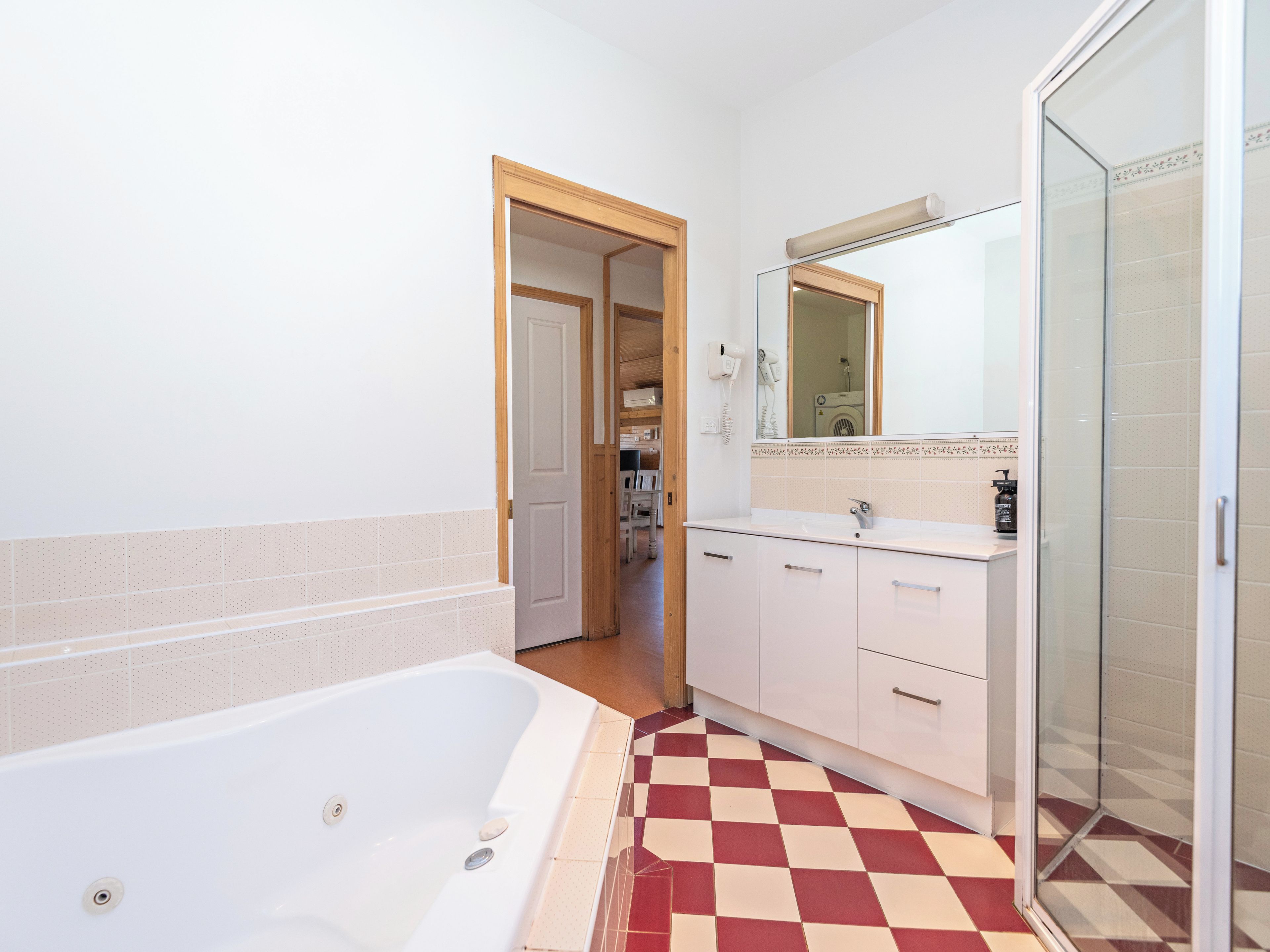 A bathroom with a bathtub, a shower, a vanity with a mirror, and a checkered floor.