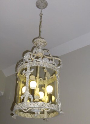 Un lustre blanc, richement décoré, doté de nombreuses ampoules.