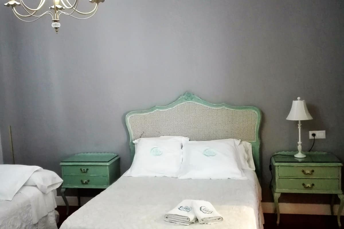 Una habitación con una cama, dos mesitas de noche, una lámpara y un candelabro.