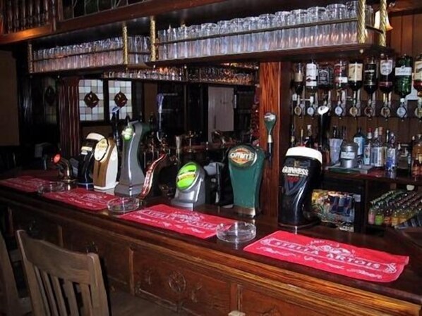 Zona de bar con múltiples grifos de cerveza, una variedad de botellas y una barra de madera.