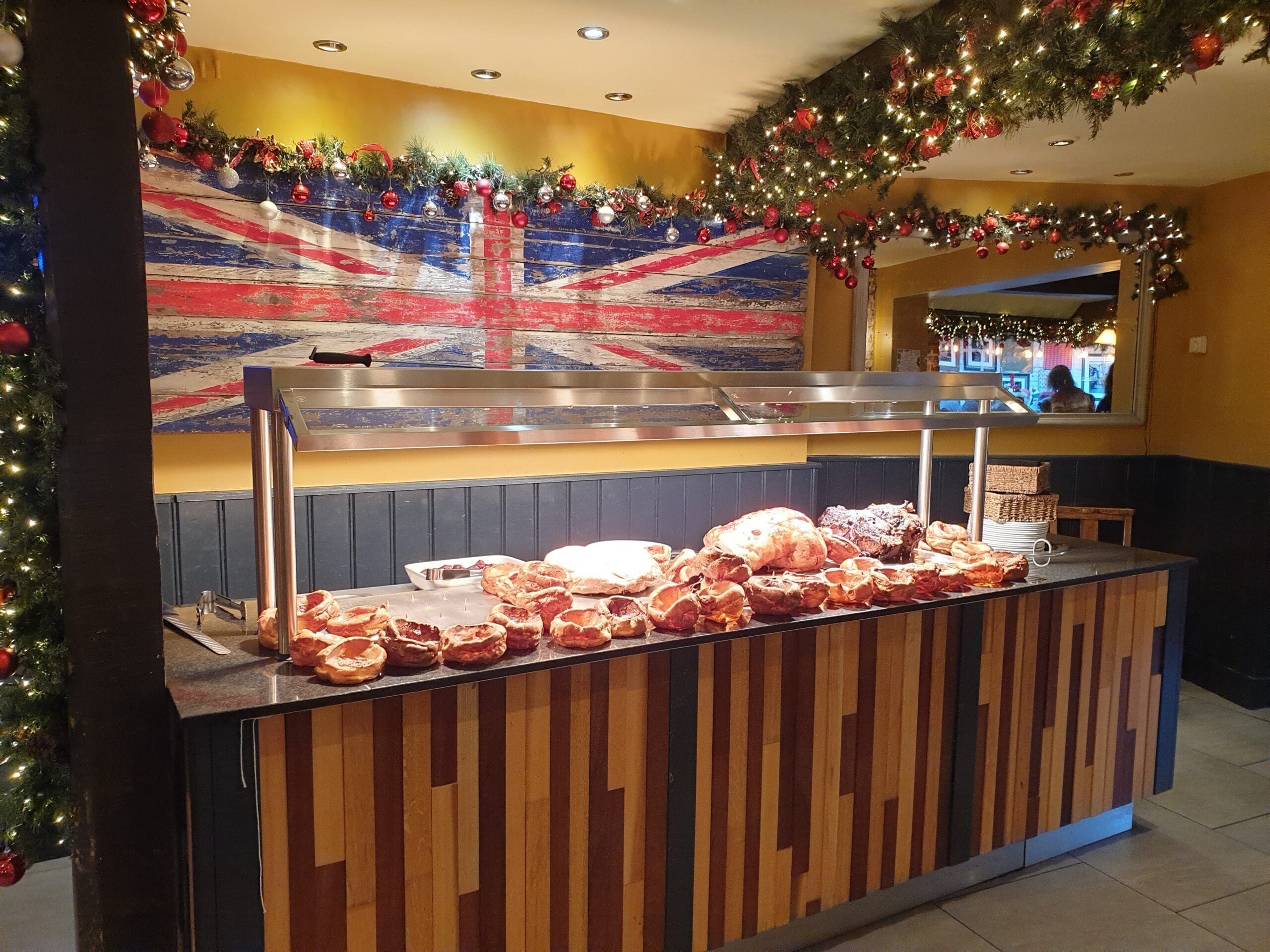 A buffet counter with various pastries and a Union Jack-themed wall decoration.