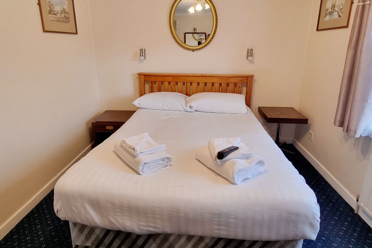 Une chambre d’hôtel avec un grand lit, une tête de lit en bois, un miroir rond et deux tables de chevet.