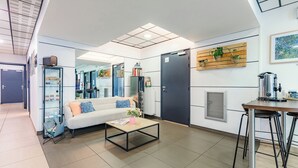 A modern living room with a sofa, coffee table, and a dining area with stools. - Appart'City Confort Angers (Angers)