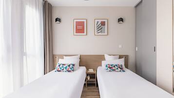 A hotel room with two beds, a nightstand, and two framed pictures on the wall.