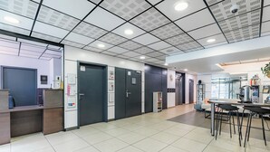A modern interior with a reception desk, private rooms, and a seating area with a table and chairs. - Appart'City Confort Angers (Angers)