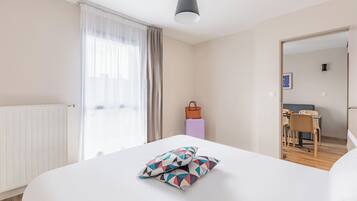 Una habitación de hotel con una cama grande, un escritorio y una silla al fondo.