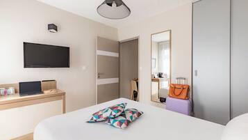Una habitación de hotel moderna con una cama, un escritorio con una computadora portátil, un televisor de pantalla plana, un espejo y una maleta.