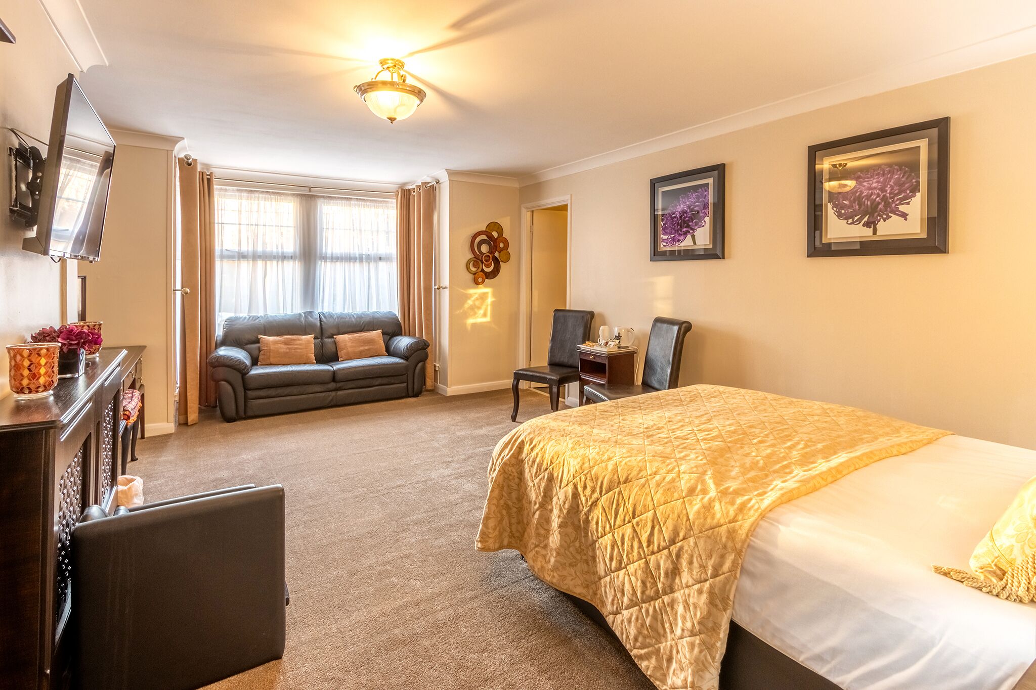 Ein Hotelzimmer mit Bett, Sofa, Schreibtisch und Fernseher.