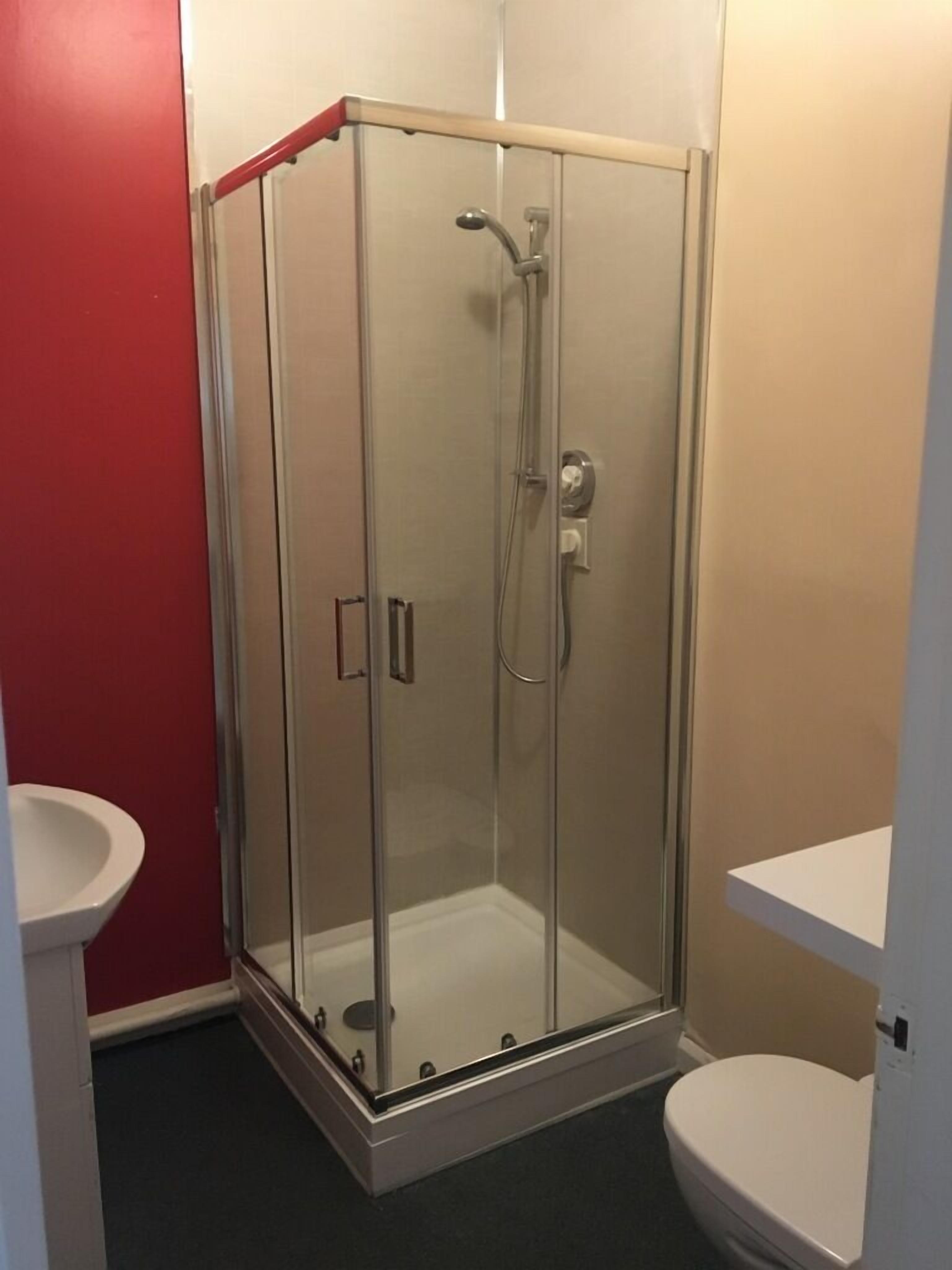 Eine Duschkabine mit Toilette und Waschbecken, alles in Weiß.