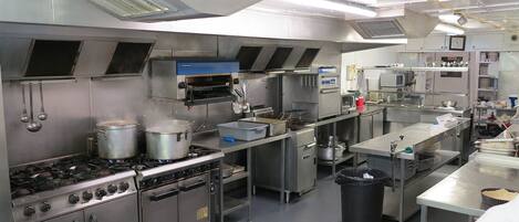 A commercial kitchen with stainless steel appliances, including a stove, oven, and microwave.