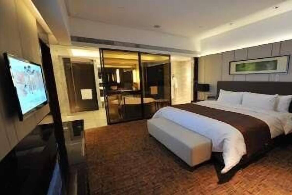 Ein modernes Hotelzimmer mit einem großen Bett, einem Flachbildfernseher, einem Schreibtisch und einer Sitzecke.