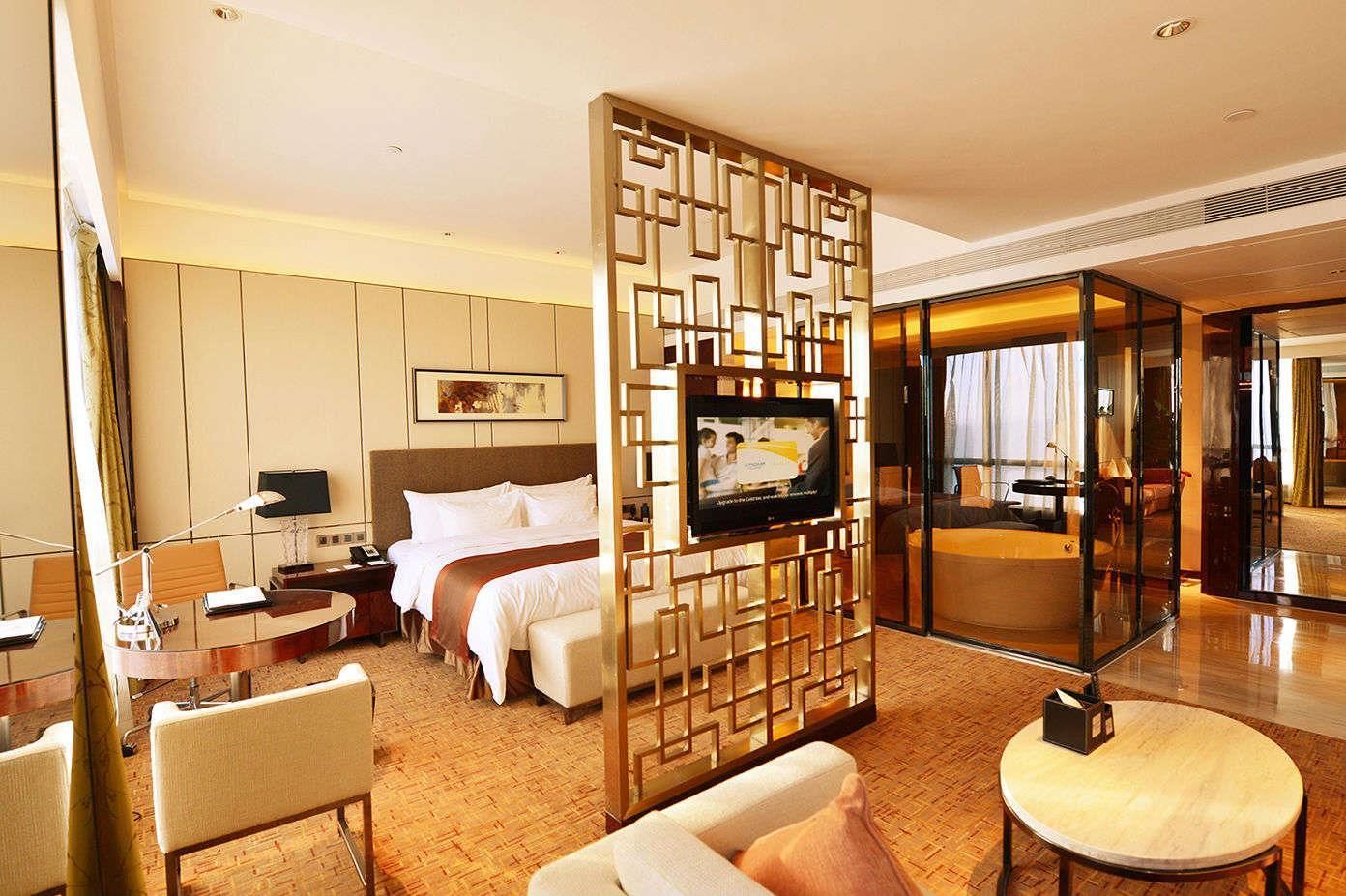 Una habitación de hotel con una cama, televisión, escritorio y zona de estar.
