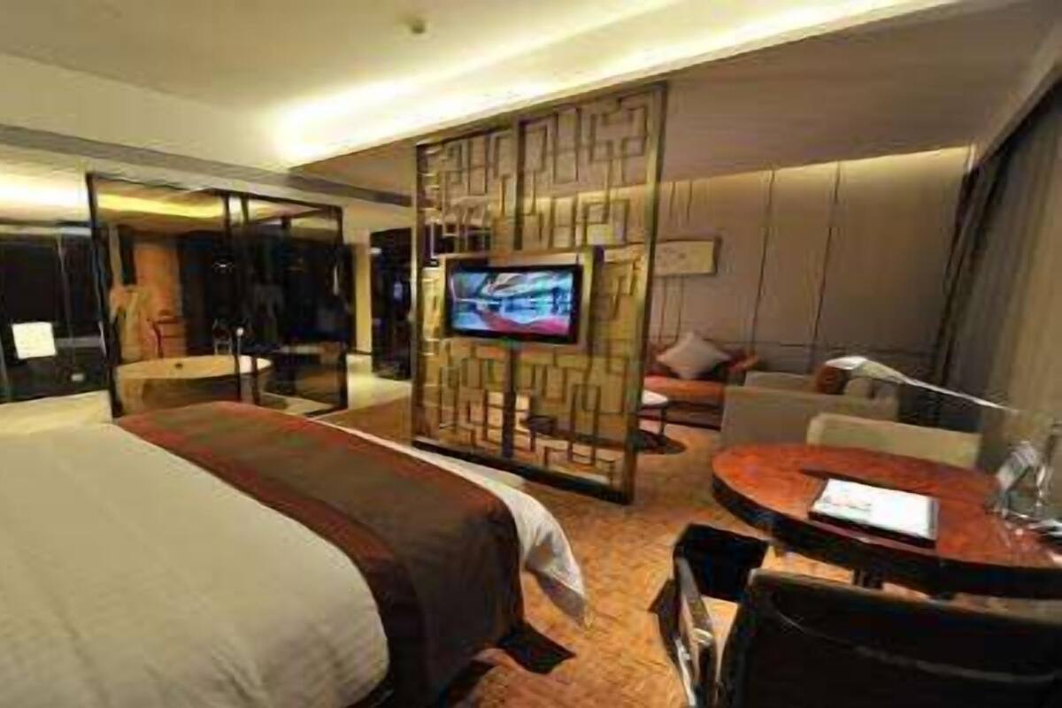 Ein Hotelzimmer mit einem großen Bett, einem Fernseher, einem Schreibtisch und einer Sitzecke.