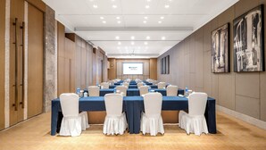 Une salle de conférence équipée de plusieurs tables, de chaises et d’un écran de projection.