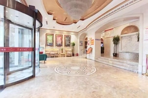 Un vestíbulo de hotel con una recepción, una araña y un suelo estampado.