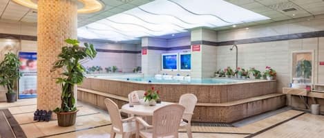 A hotel lobby with a reception desk, seating area, and potted plants.