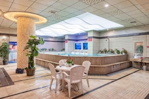 Un hall de hotel con mostrador de recepción, zona de estar y plantas en macetas.