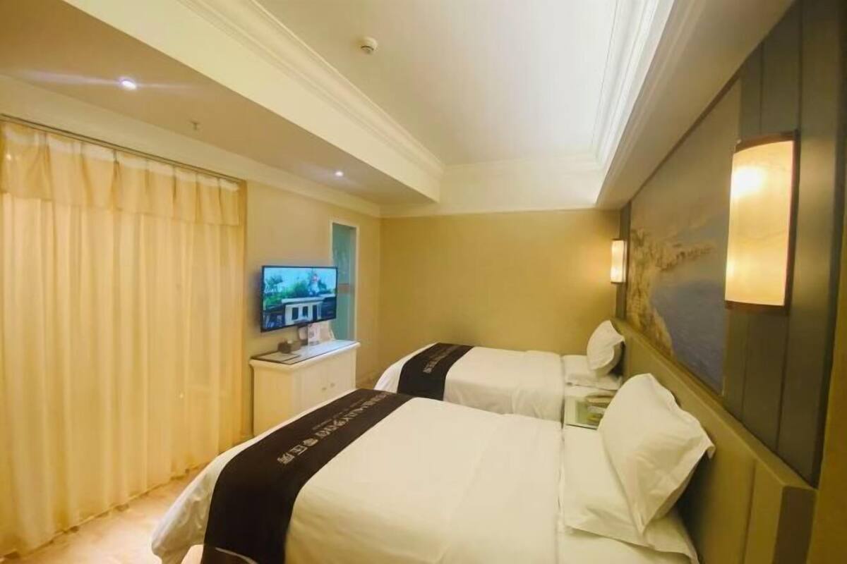 A hotel room with two beds, a television, and a desk.