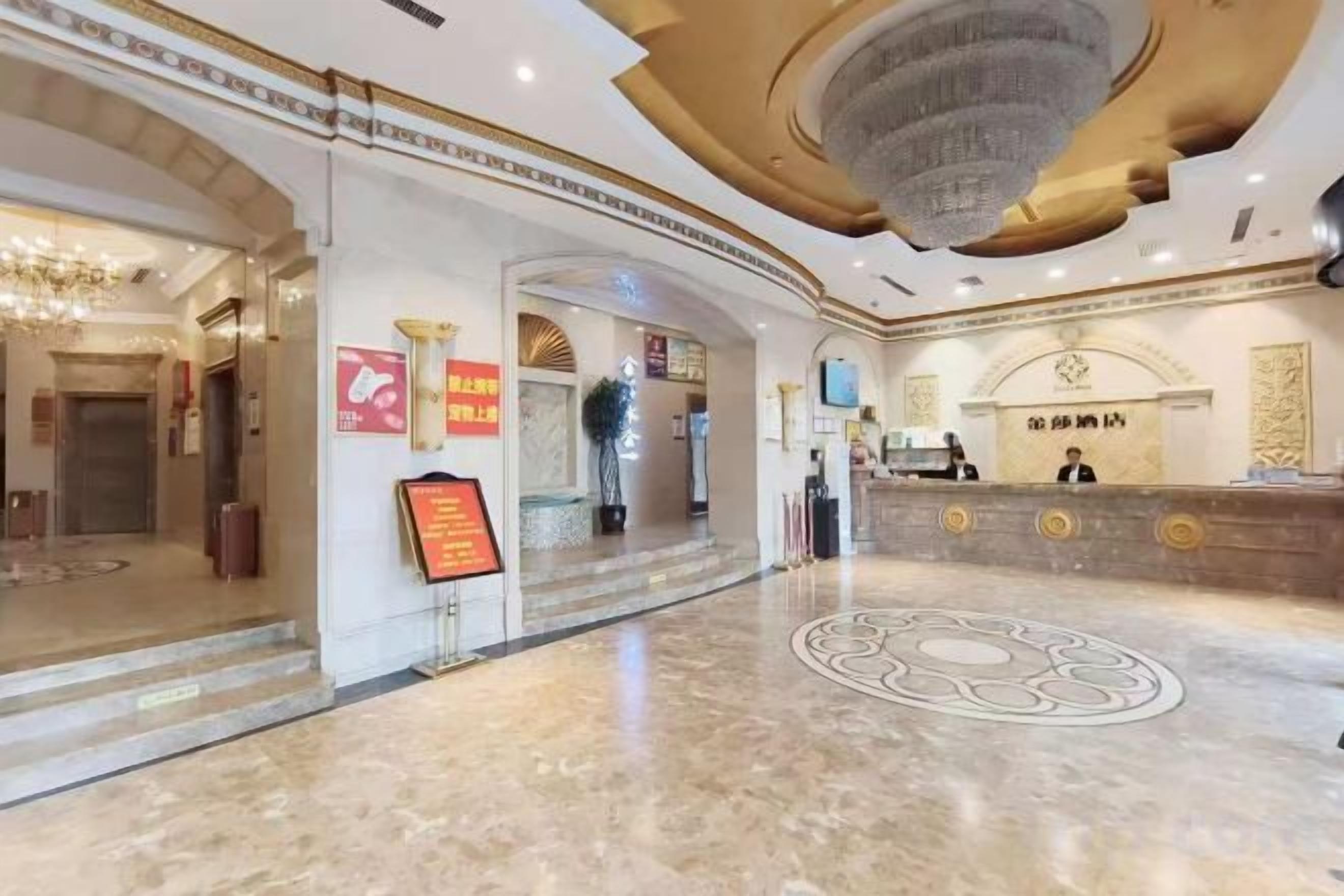 Un vestíbulo de hotel con una recepción, una araña y un suelo de mármol.