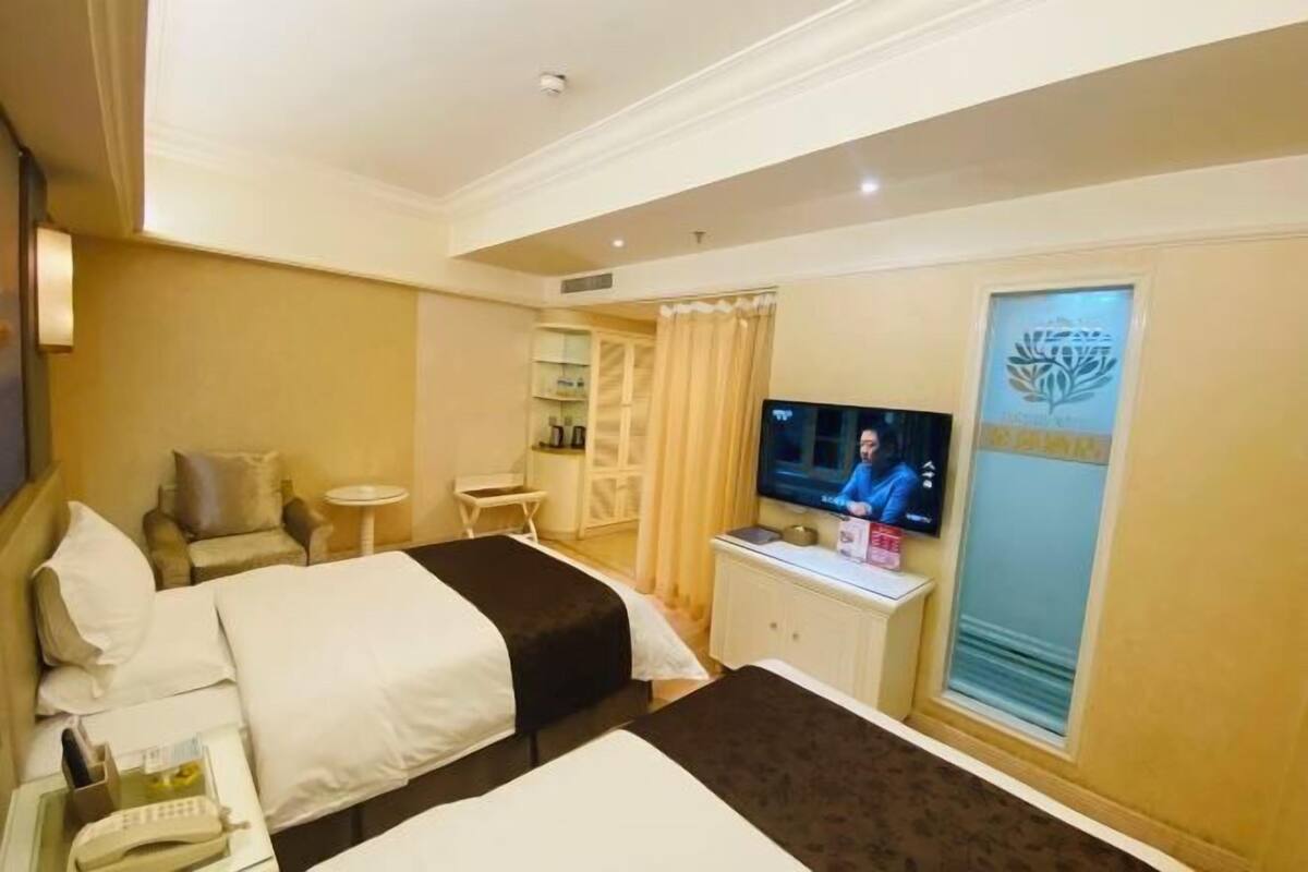 A hotel room with two beds, a television, a small table, and a cabinet.