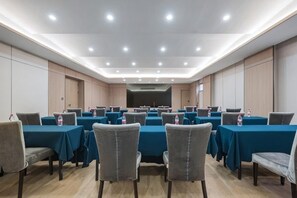 Ein Konferenzraum mit mehreren Tischen und Stühlen, ausgestattet mit Wasserflaschen.