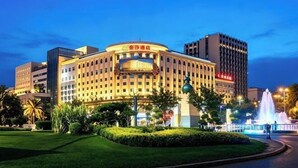 A large hotel with a prominent curved facade, multiple floors, and a well-maintained garden area.