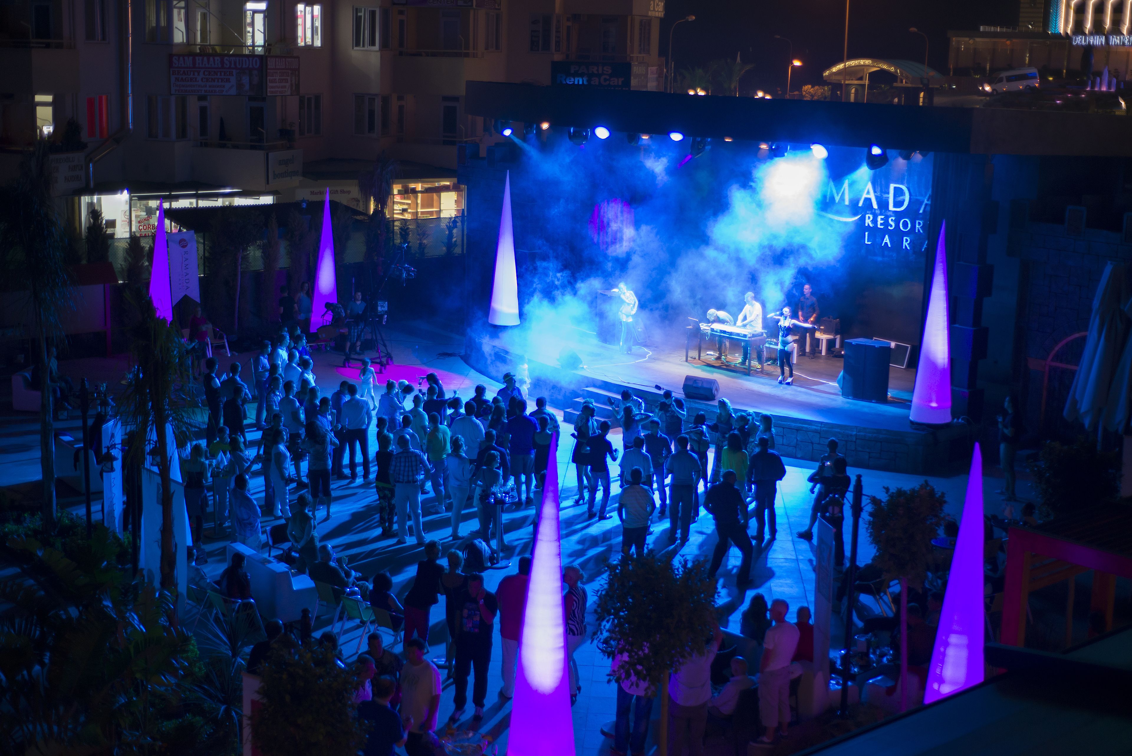 A stage with a "MAD RESORT LAR" sign, surrounded by a crowd of people.