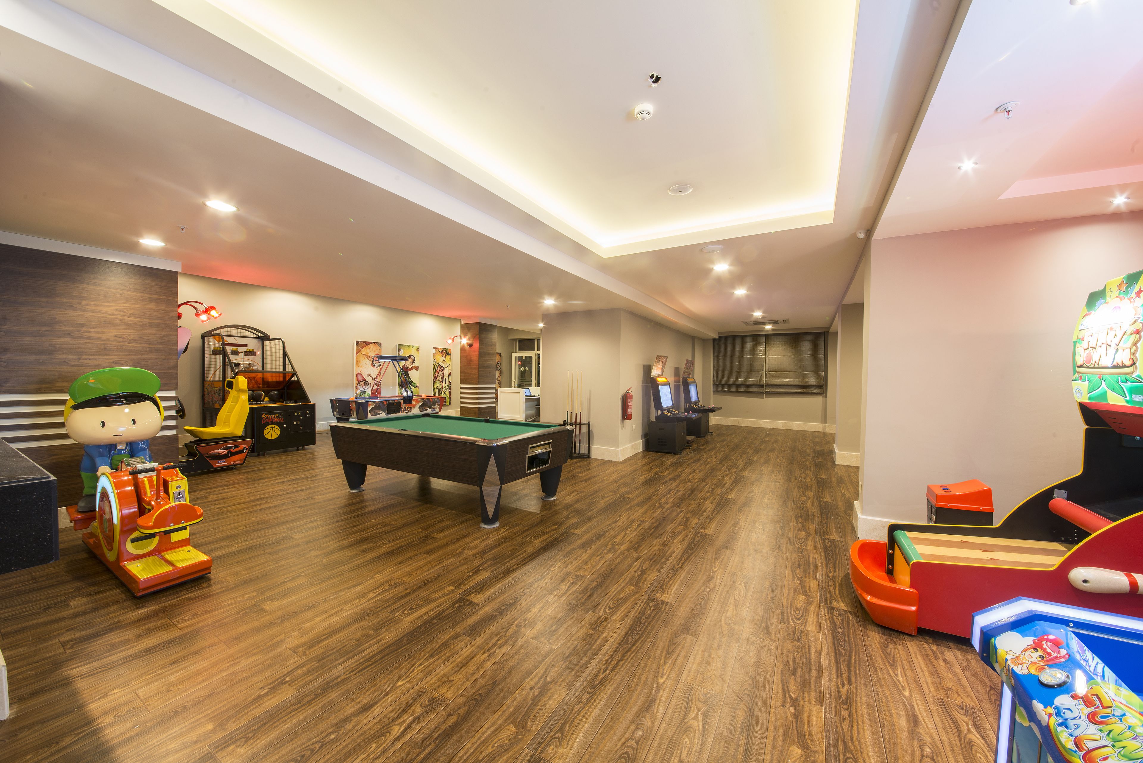 A spacious indoor recreational area with a pool table, arcade games, and a toy train.