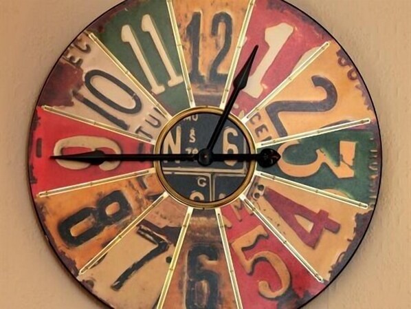 A wall clock with a vintage design, featuring numbers and letters in a colorful, distressed finish.