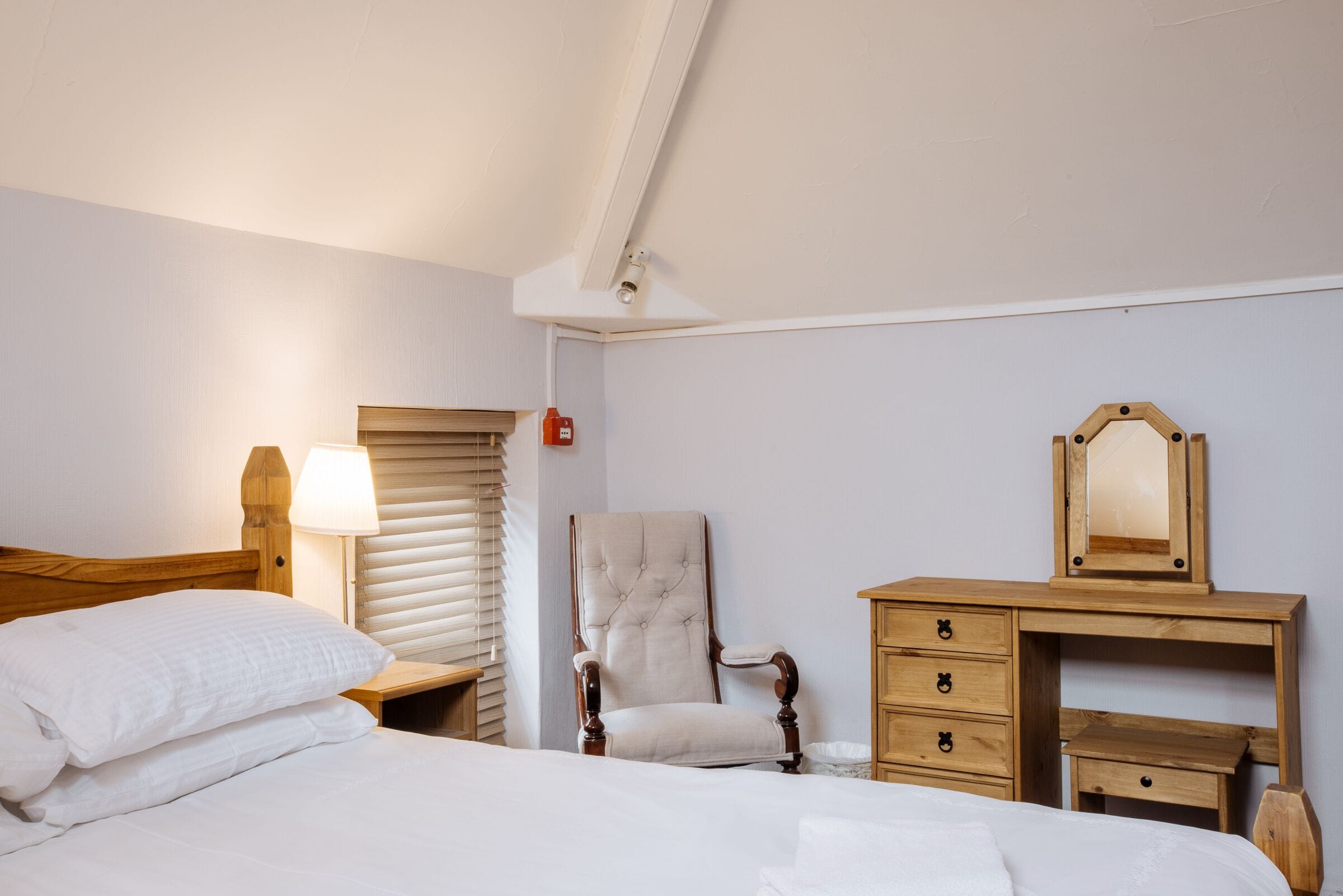 Une chambre à coucher avec un lit, une chaise, une commode et un miroir.