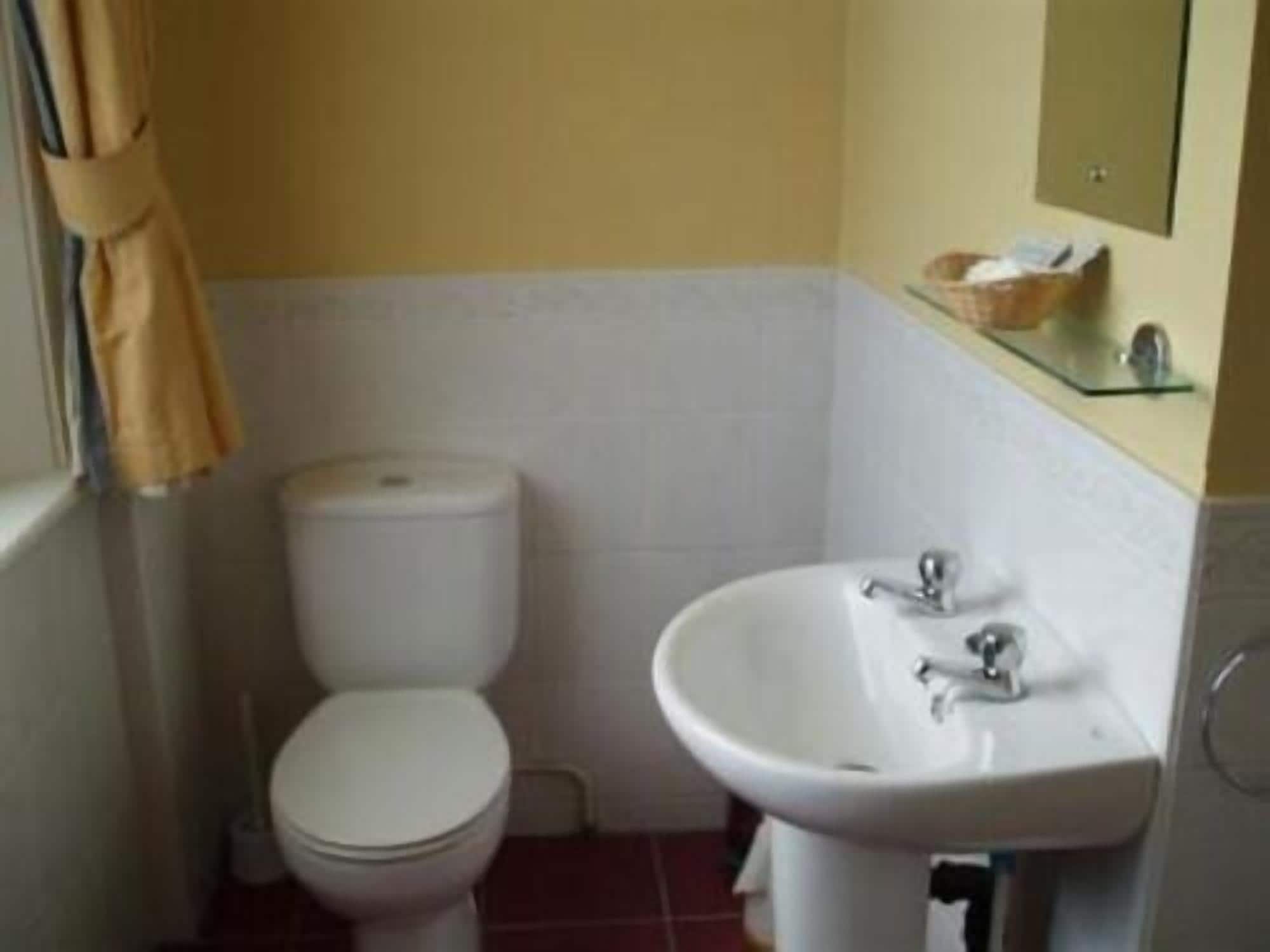 A small bathroom with a toilet, a sink, and a mirror.