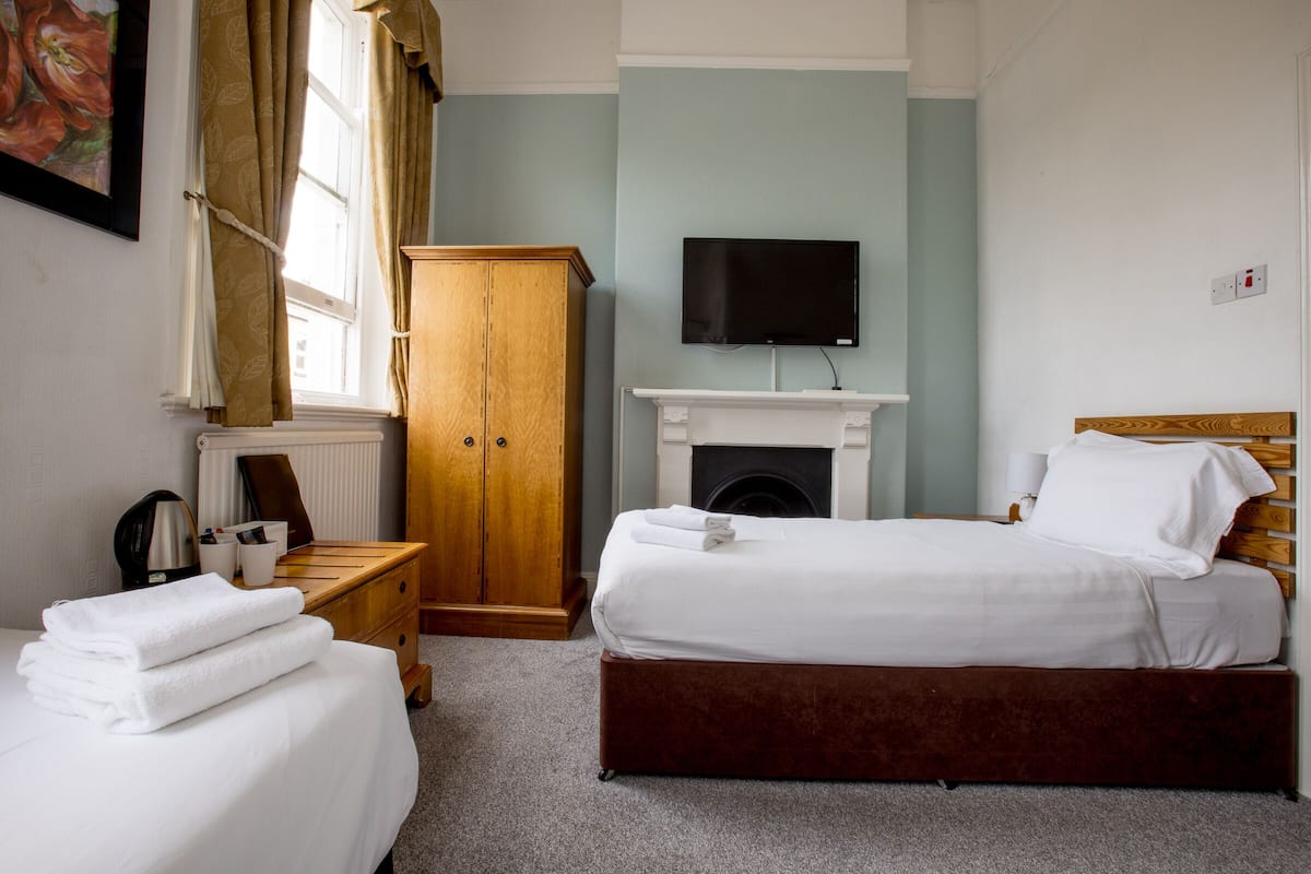 A bedroom with a bed, a TV, a fireplace, and a wooden wardrobe.