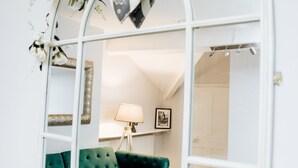 Una habitación con un sofá verde, una mesa de centro de madera y un espejo con detalles florales.