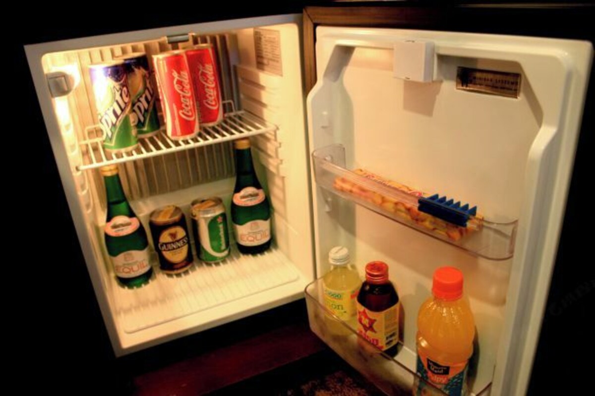 A refrigerator with shelves containing various beverages, including beer, soda, and juice.