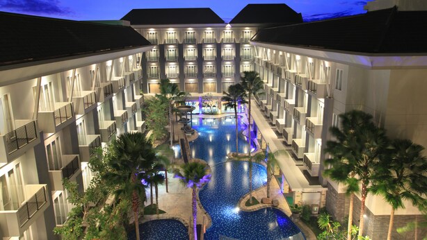 A hotel with a central swimming pool, multiple balconies, and palm trees. - Swiss-Belhotel Danum Palangkaraya (Palangkaraya)