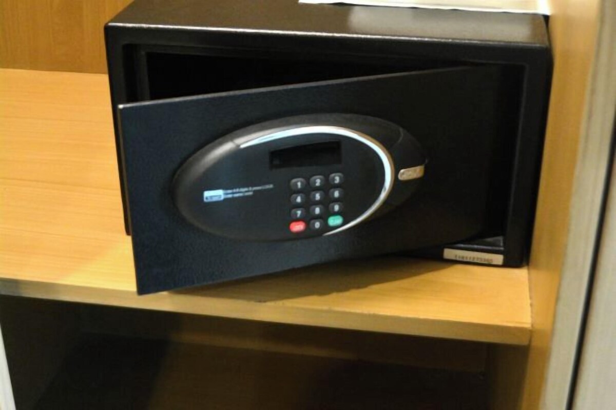 A black electronic device with a keypad and a screen, likely a control panel or security system, on a wooden surface.