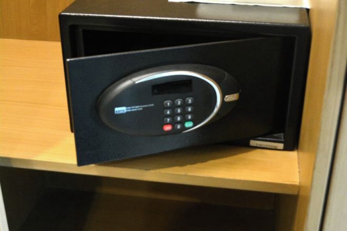 A black electronic device with a keypad and a screen, likely a control panel or security system, on a wooden surface.
