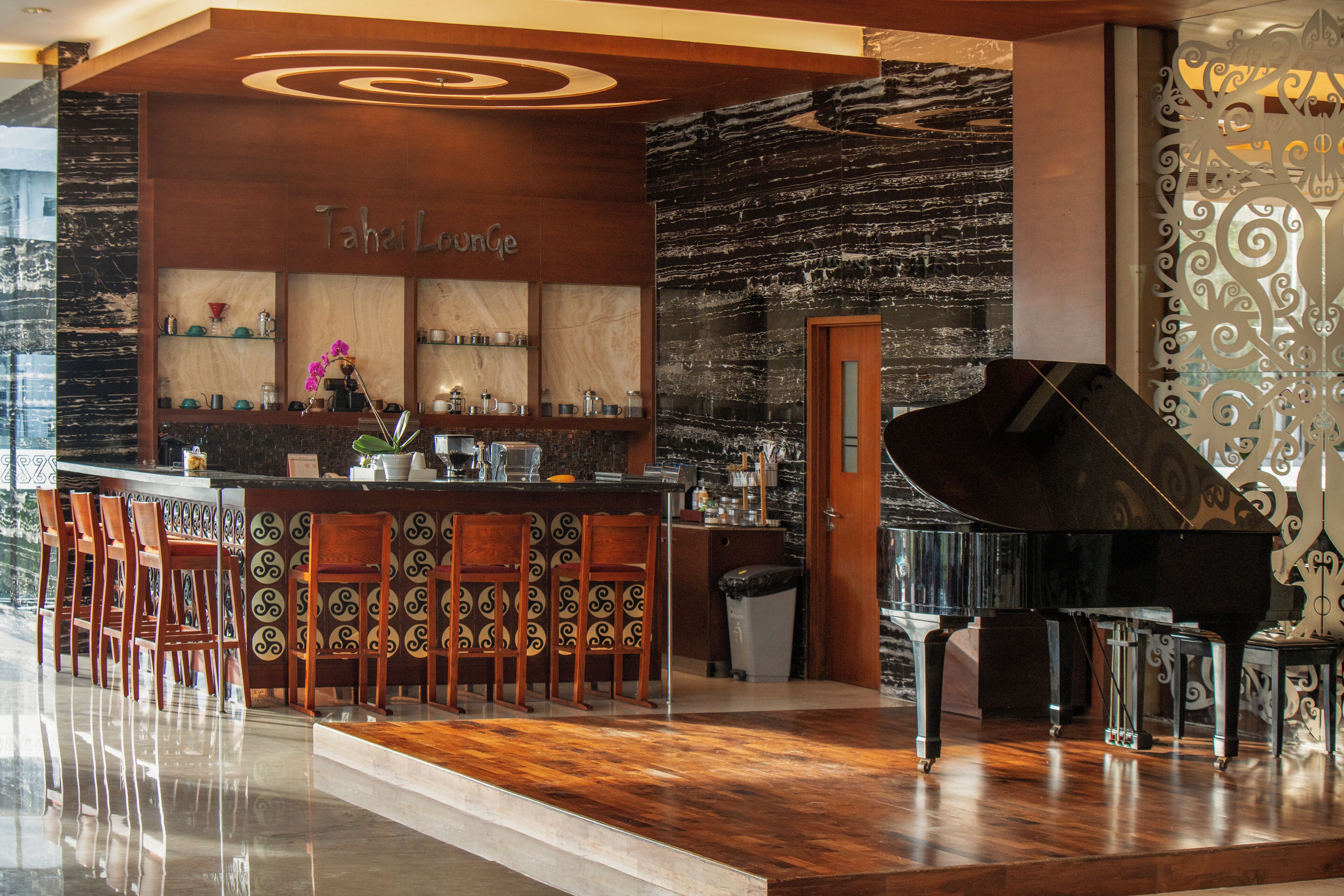 A bar area with a piano, wooden chairs, and a counter with various items.