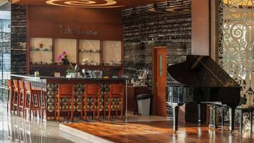 A bar area with a piano, wooden chairs, and a counter with various items.