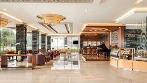 A modern hotel lobby with a piano, seating area, and a bar. - Swiss-Belhotel Danum Palangkaraya (Palangkaraya)