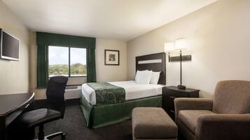 Une chambre d’hôtel équipée d’un lit, d’un bureau, d’une chaise et d’une table de chevet avec des lampes.