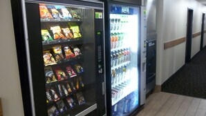 Máquina de vendas com lanches e água em um corredor.