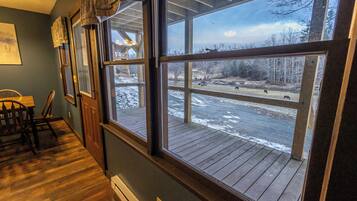 A room with large windows, wooden flooring, and a view of a snowy outdoor area.