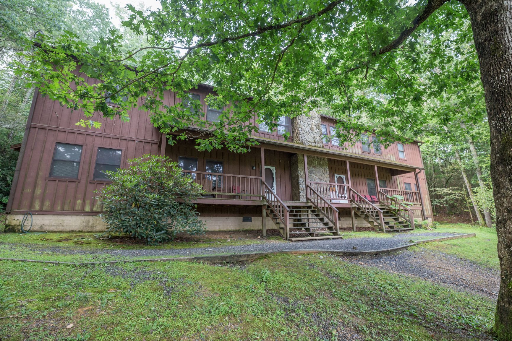 A rustic cabin with a porch, multiple windows, and a stone foundation.