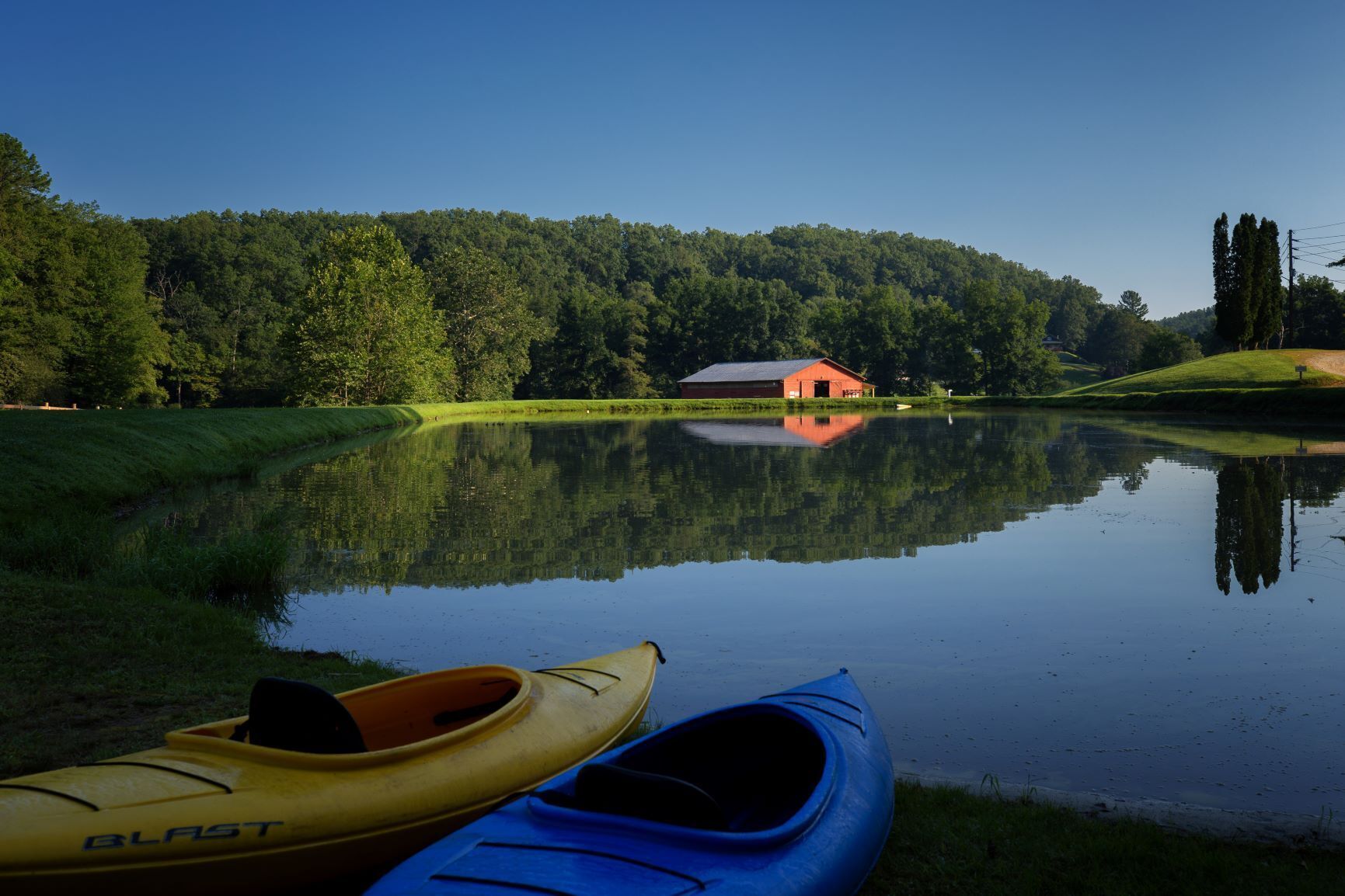 Un lac paisible, avec un bâtiment rouge et deux kayaks sur la rive.