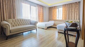 Une chambre d’hôtel avec un canapé, un lit, une petite table avec un panier et des rideaux.